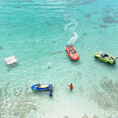 Two people with jet skis and car-shaped boats on clear turquoise water.